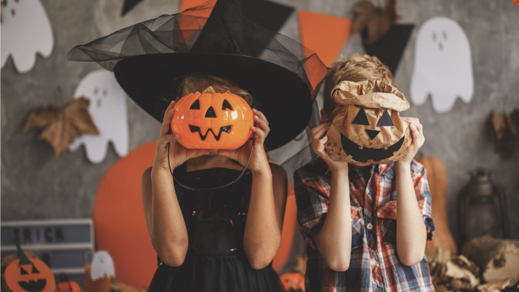 Two kids in halloween costumes in a room full of halloween decorations